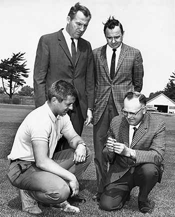 Four men inspecting a turfgrass sample.