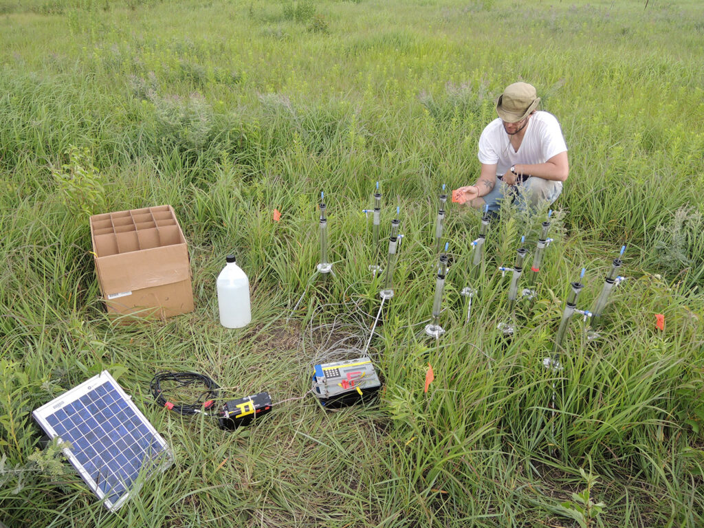 Researcher in a grassy field with testing equipment.